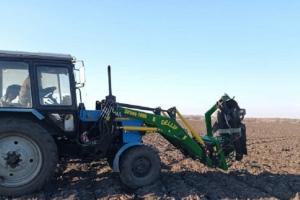 Трактор забирає залишки ворожої техніки з поля